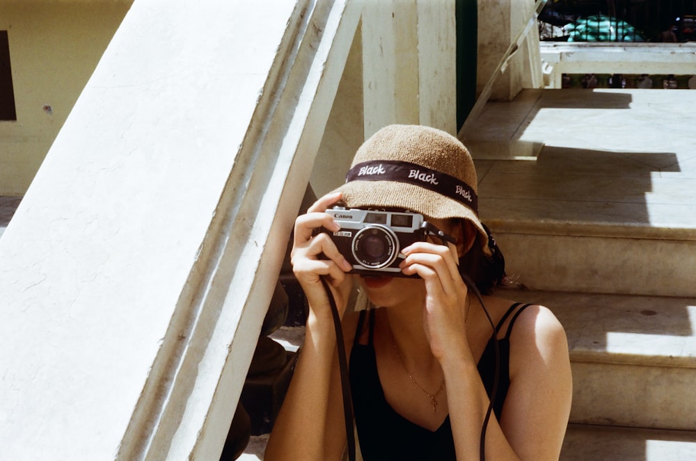 woman in black tank top holding black and silver dslr camera