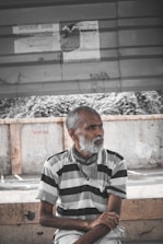man in black and white stripe dress shirt sitting on concrete bench