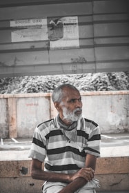 man in black and white stripe dress shirt sitting on concrete bench
