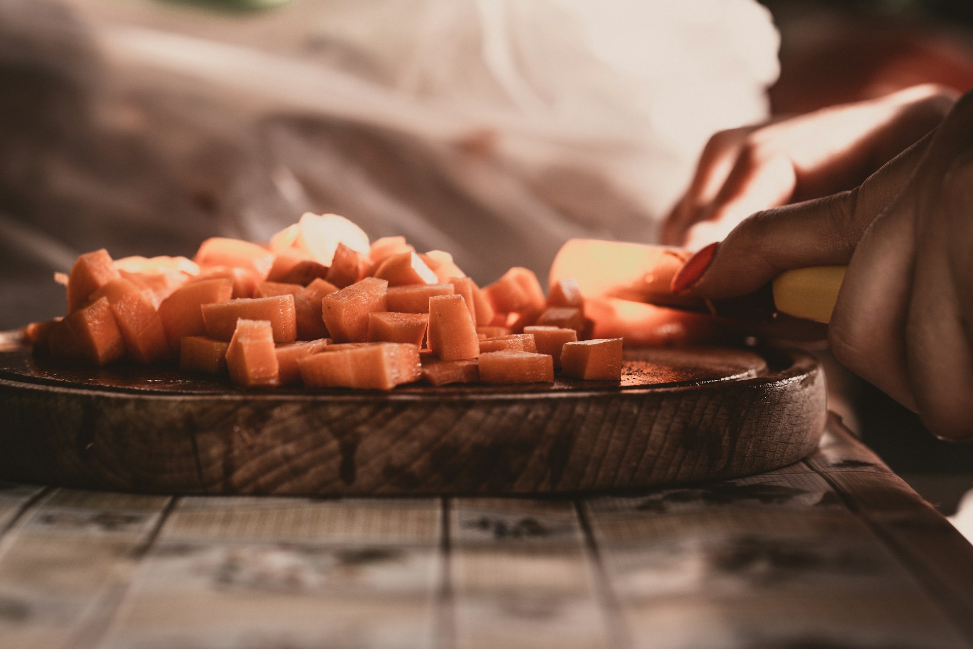 person slicing meat on brown wooden chopping board