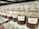 A row of glass jars filled with different types of coffee beans, each labeled with a specific blend, such as Viennese Blend, Oriental Espresso Blend, and Arabica Plantation-AAA. The jars are neatly aligned on a glass shelf, and the coffee beans inside are varying shades of brown.