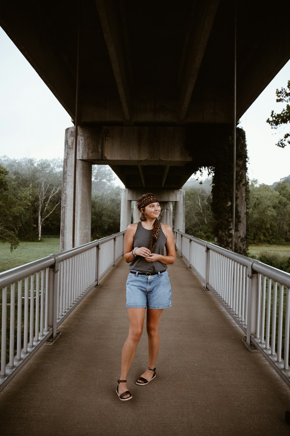 woman in blue denim shorts standing on bridge during daytime