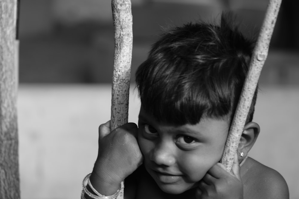 Graustufenfoto eines Jungen, der sich an einem Ast festhält
