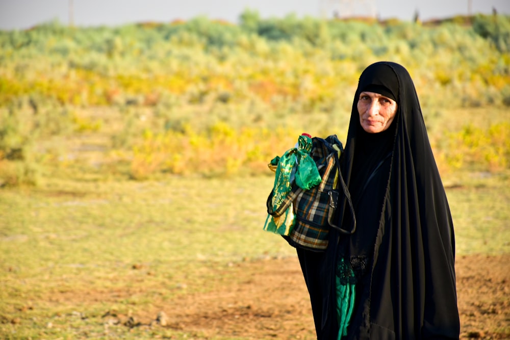 woman in black hijab standing on brown field during daytime