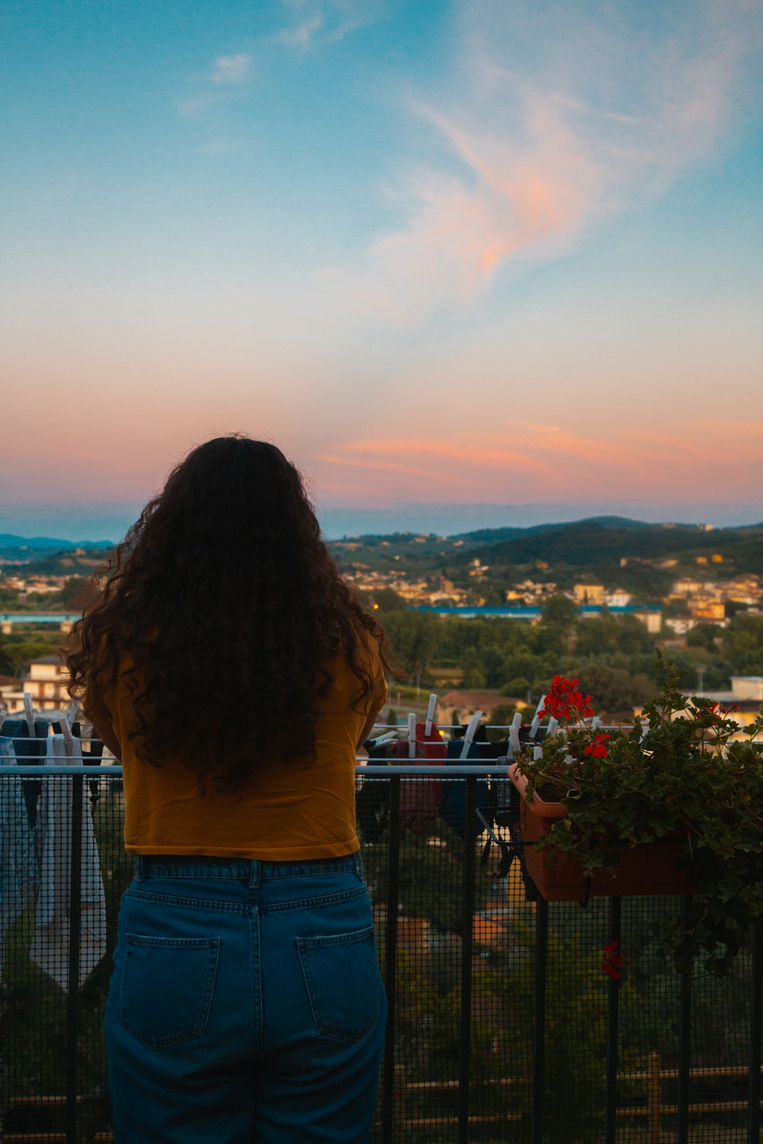 woman in white shirt standing on top of building looking at city during daytime