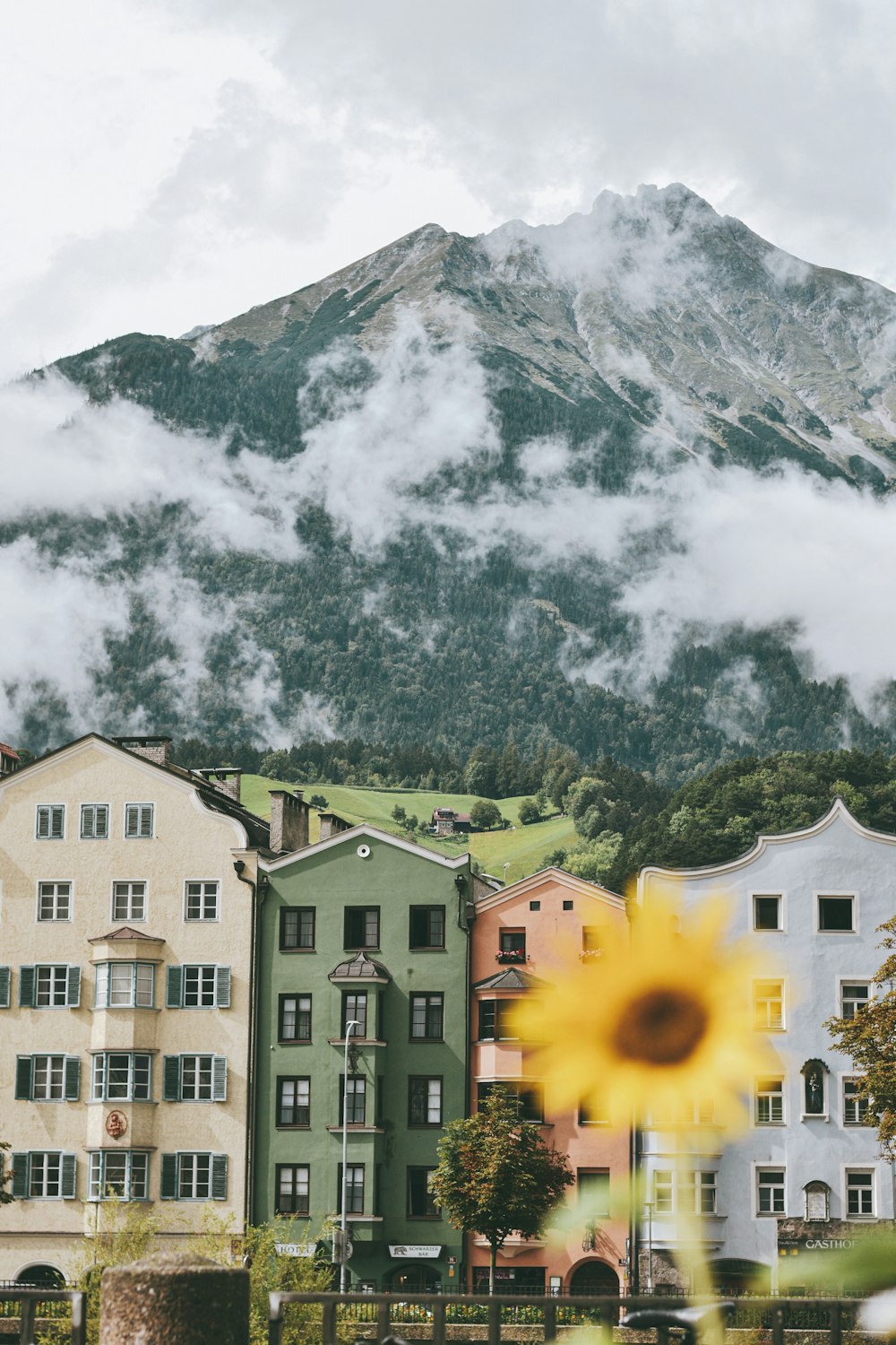 Bâtiments en béton blanc et brun près de la montagne sous des nuages blancs pendant la journée