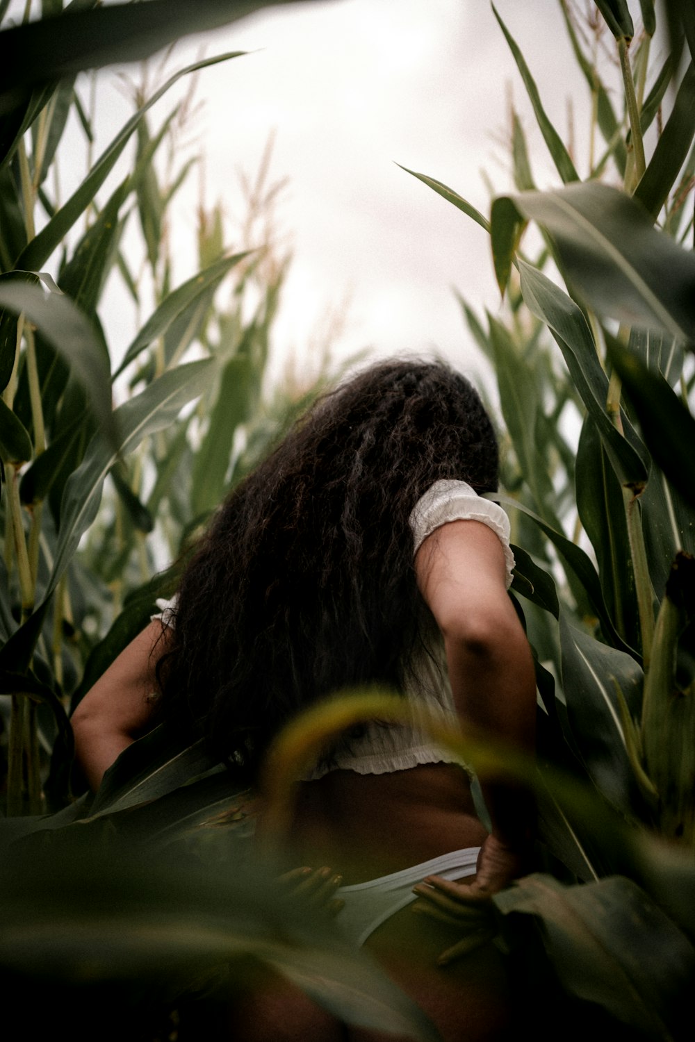 woman in white shirt standing near green plants during daytime