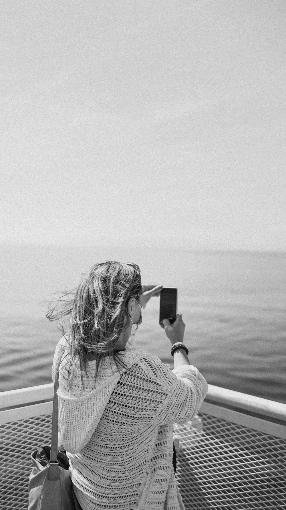 woman in white and black checkered shirt holding black smartphone