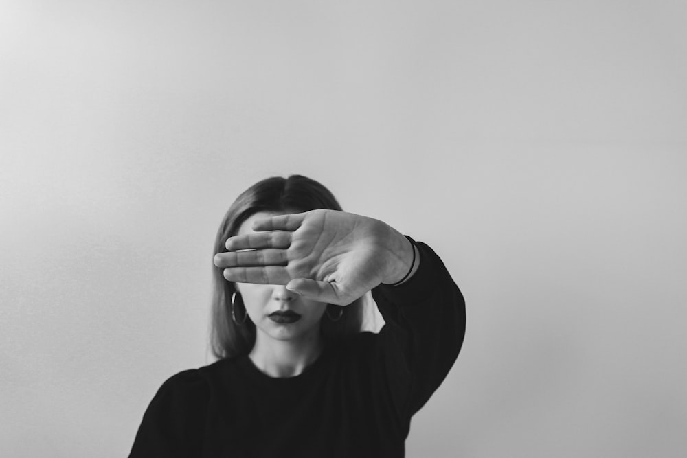 grayscale photo of man in long sleeve shirt covering his face