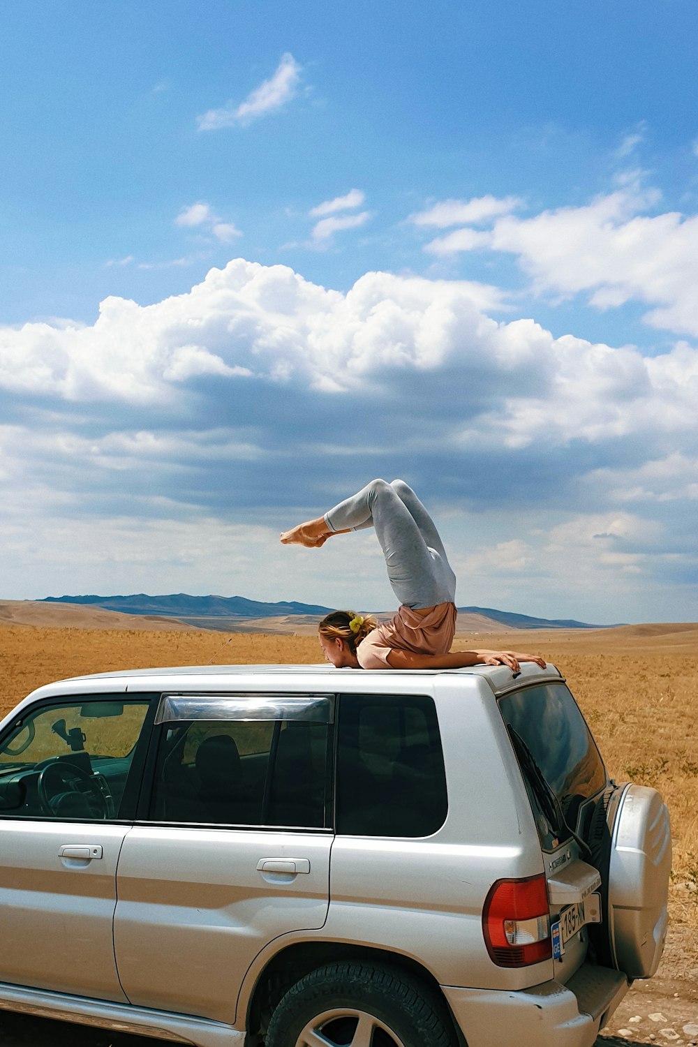 person in white long sleeve shirt and brown pants sitting on white car during daytime