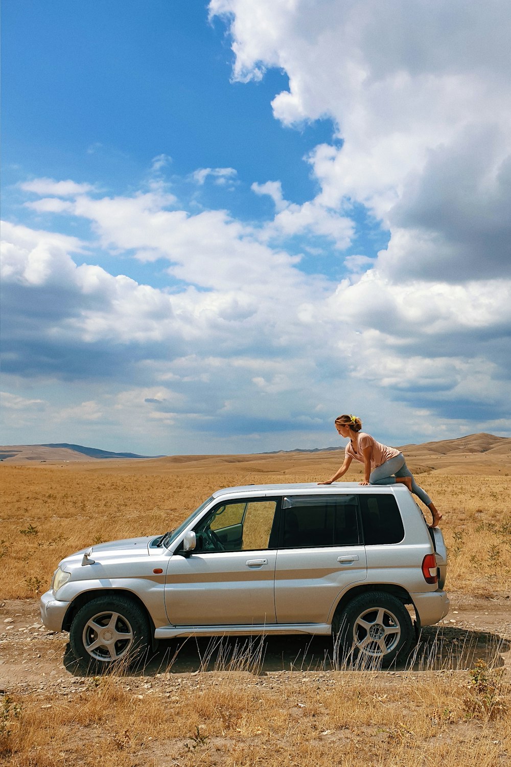 woman in white suv on brown field under white clouds and blue sky during daytime