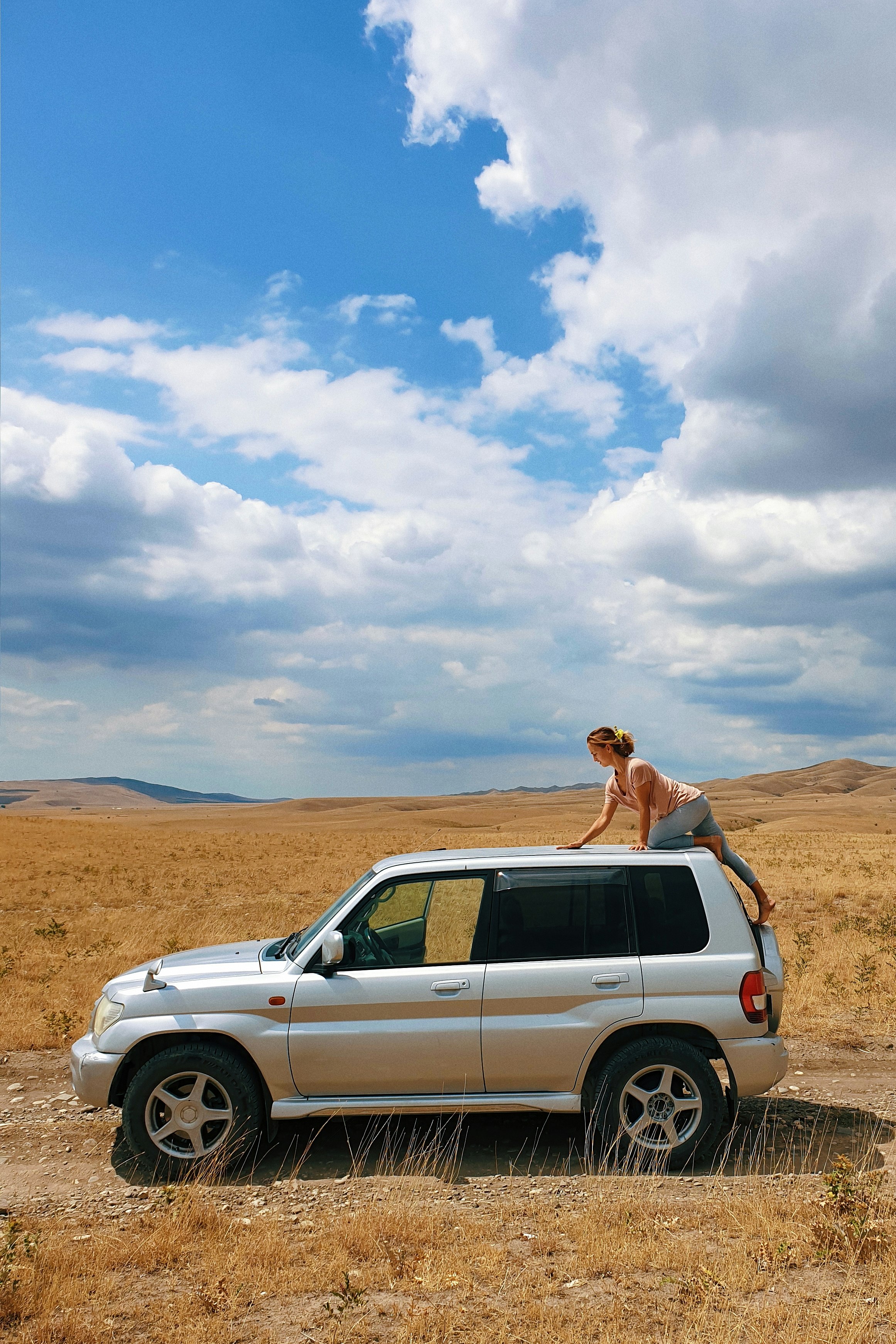 woman in white suv on brown field under white clouds and blue sky during daytime