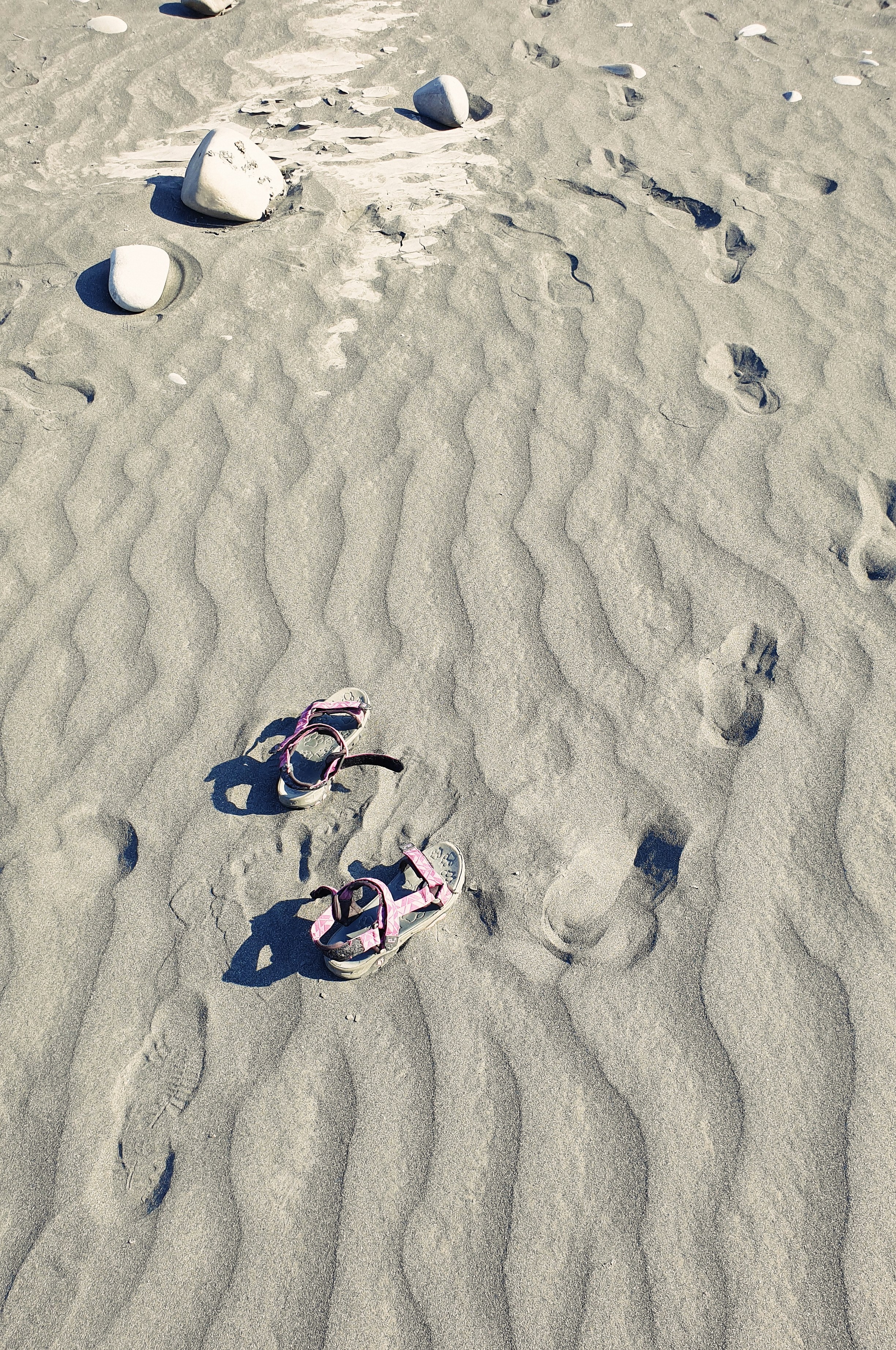 a pair of pink shoes sitting on top of a sandy beach