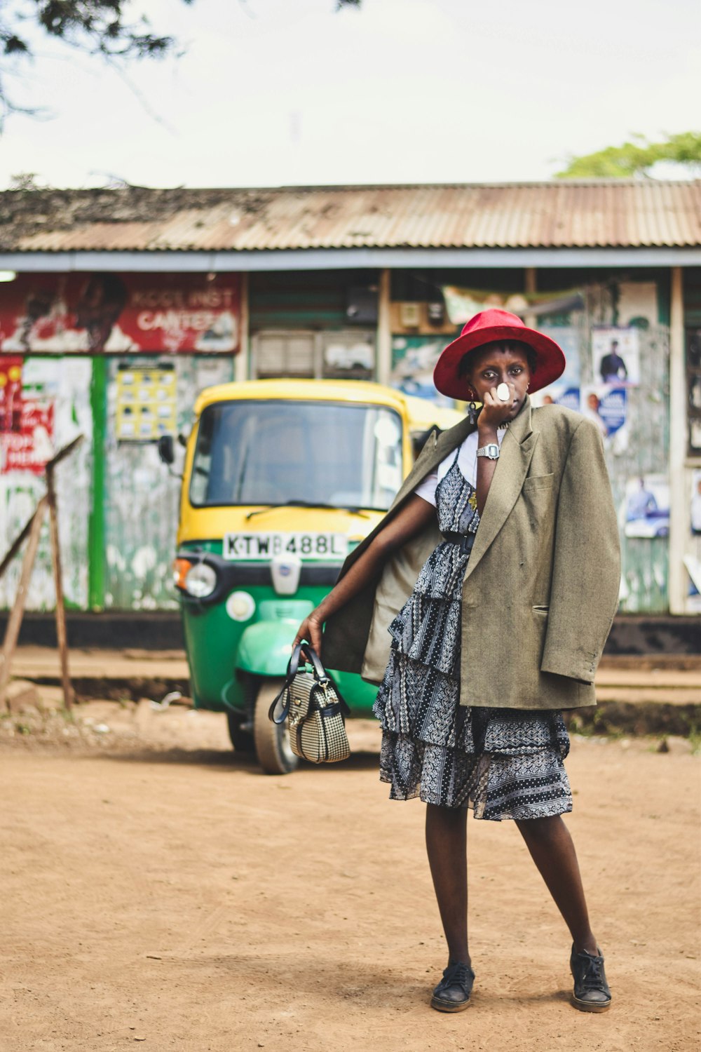 woman in grey coat standing beside green and yellow volkswagen beetle