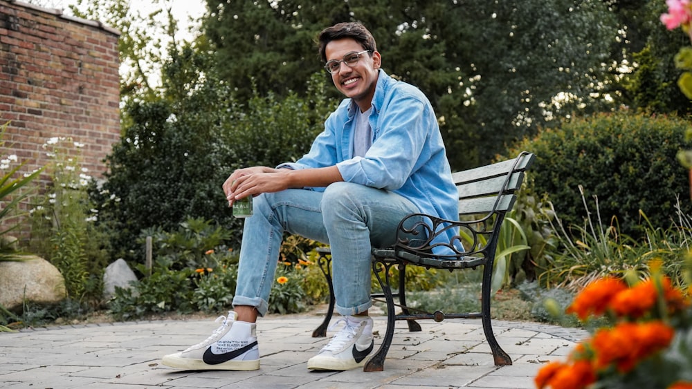 man in blue denim jacket sitting on black metal bench