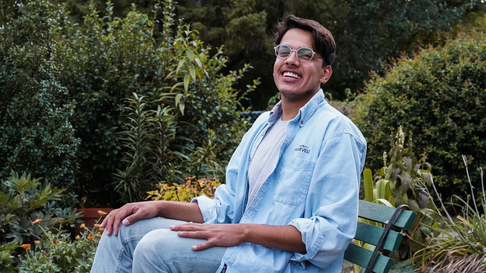 man in blue dress shirt sitting on green wooden bench