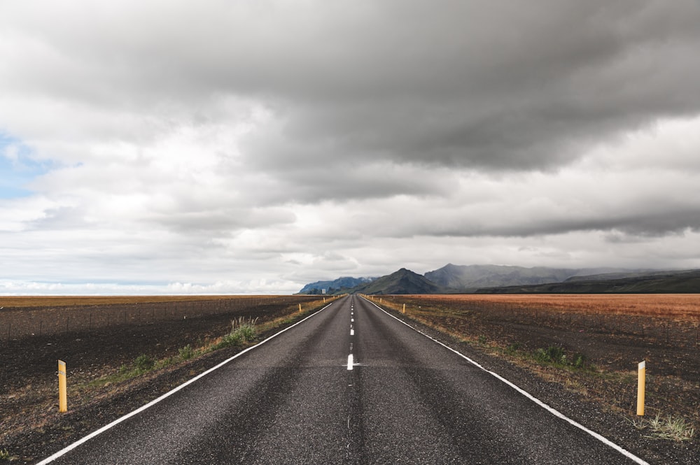 route goudronnée grise sous un ciel nuageux gris pendant la journée