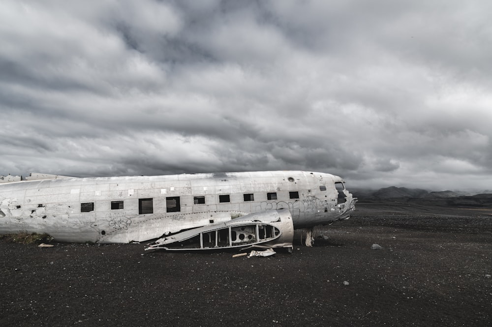 white and black plane on brown sand under white clouds during daytime