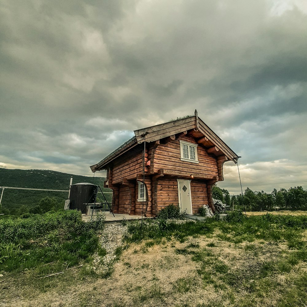 brown wooden house on green grass field under gray cloudy sky during daytime