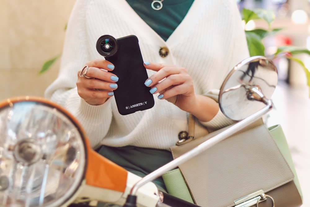 woman in white blazer holding black iphone 5