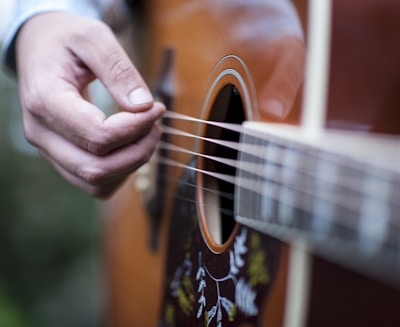 person playing brown acoustic guitar