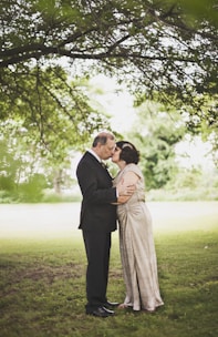 man and woman kissing on green grass field during daytime