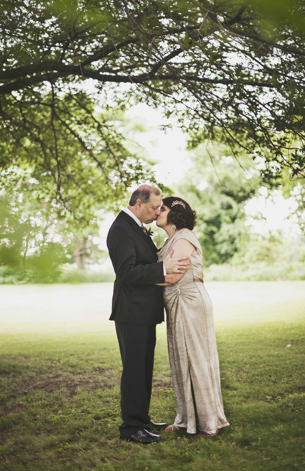 man and woman kissing on green grass field during daytime