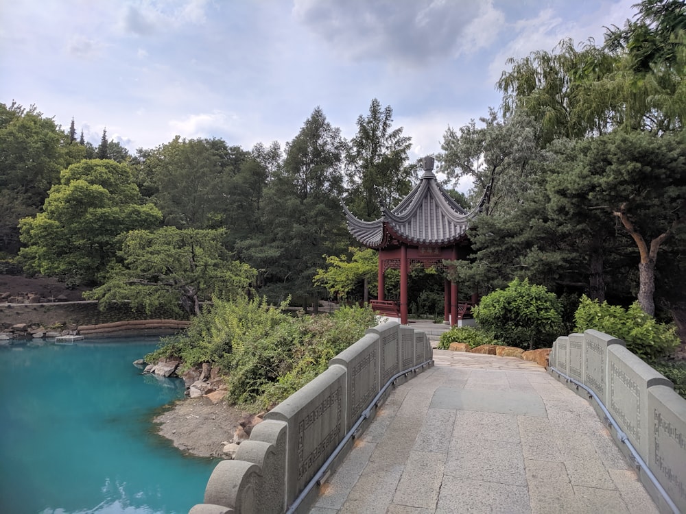 brown and black wooden gazebo near green trees and river during daytime