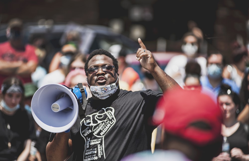 man in black and white crew neck t-shirt raising his right hand