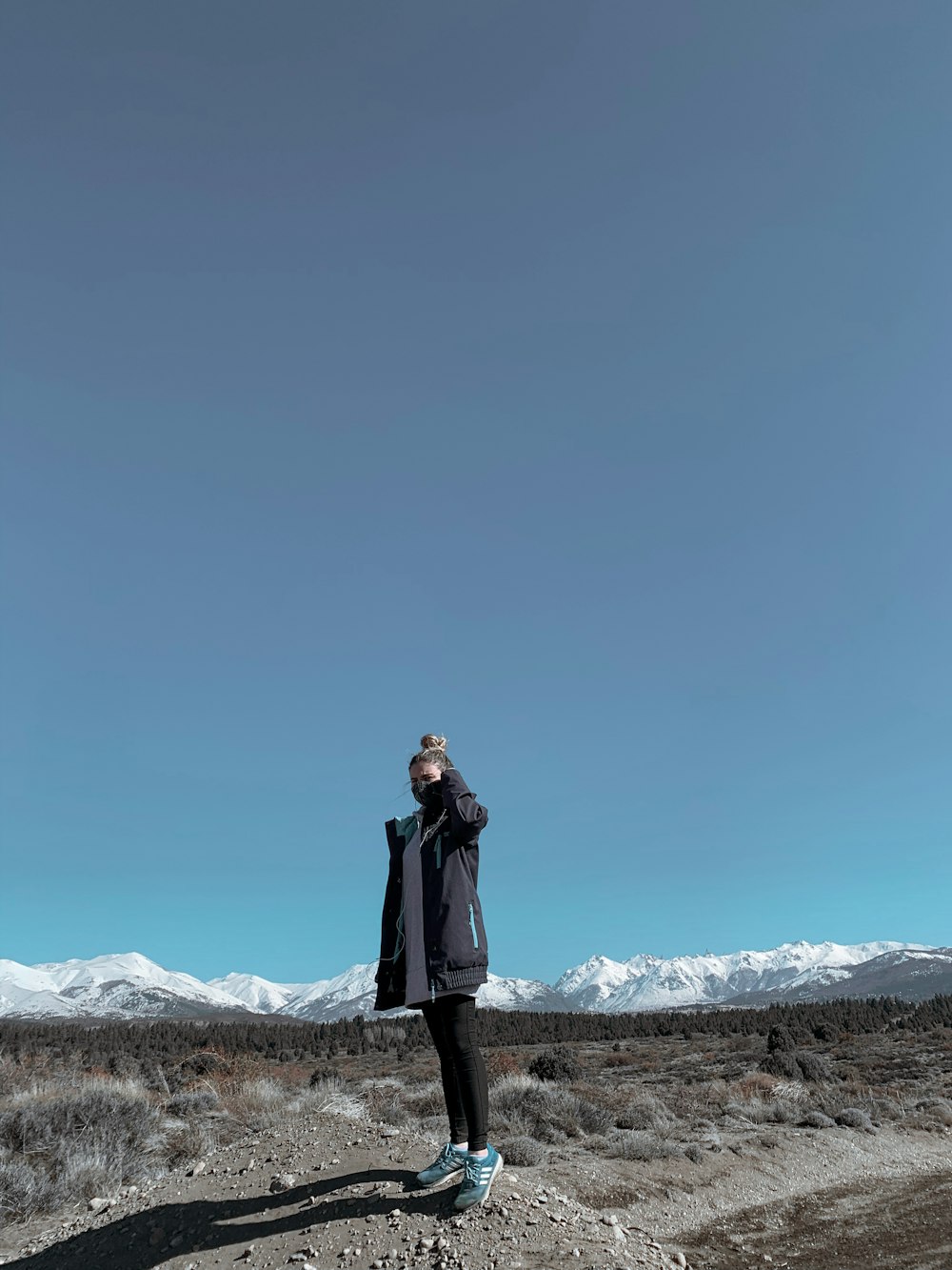 Frau im schwarzen Mantel tagsüber auf weißem, schneebedecktem Boden