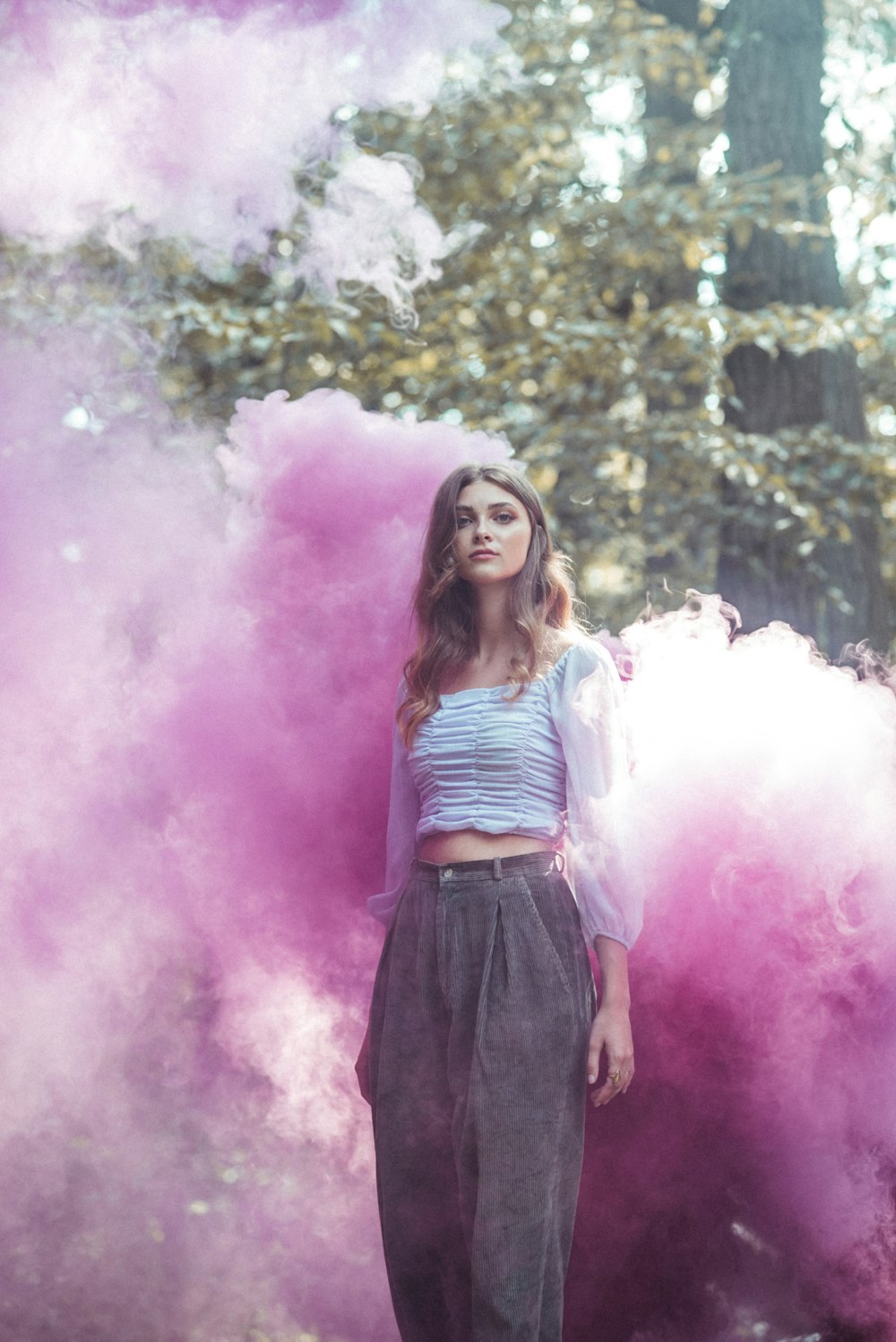 woman in white and black stripe tank top and black skirt standing on purple smoke