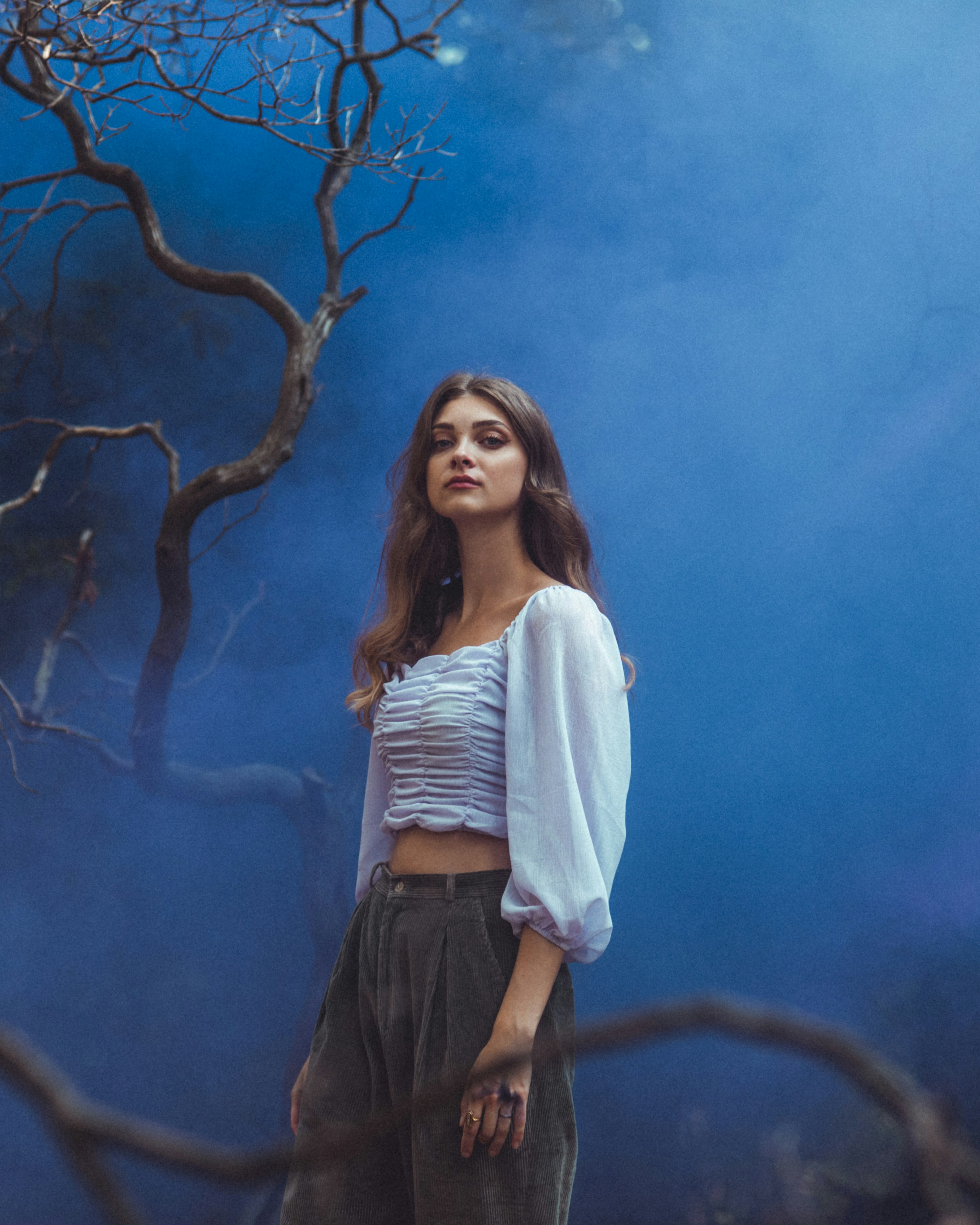 woman in white long sleeve shirt and black skirt standing beside brown tree