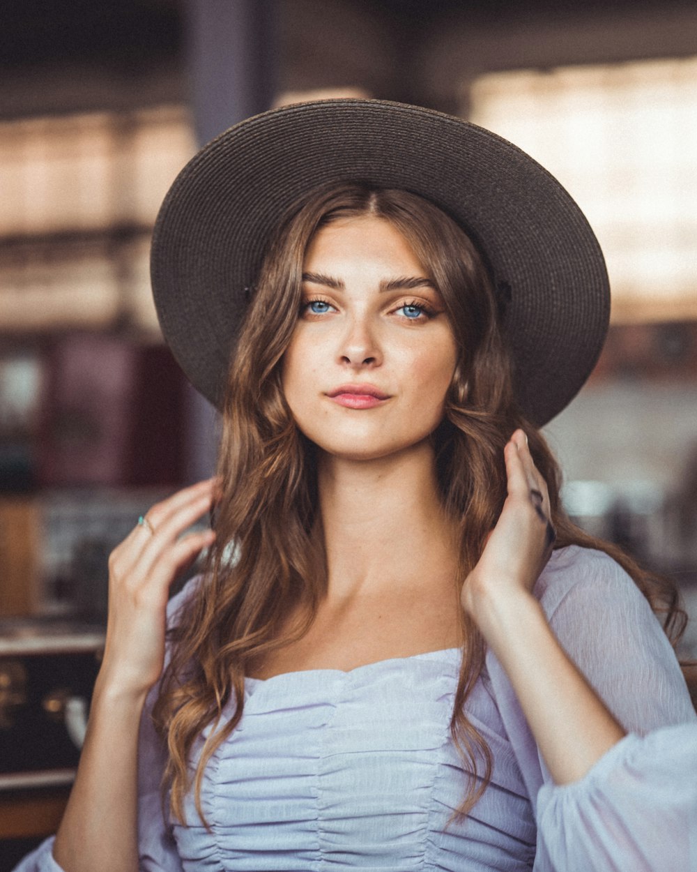 Mujer en top blanco con hombros descubiertos con sombrero fedora negro