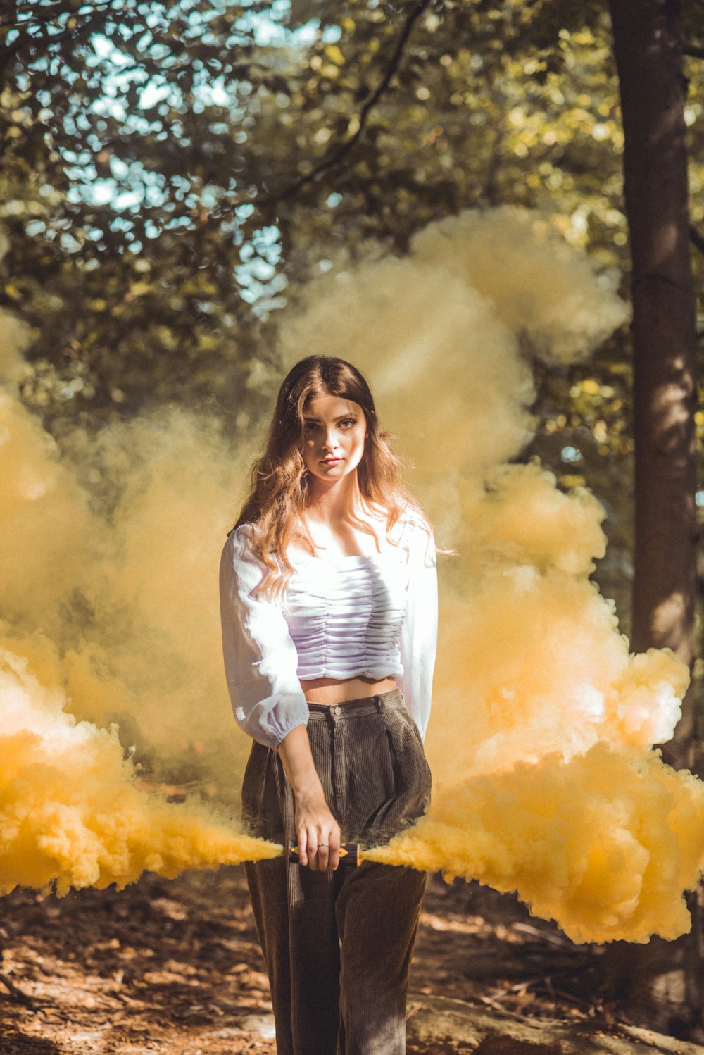 woman in white long sleeve shirt and black pants standing near green trees during daytime