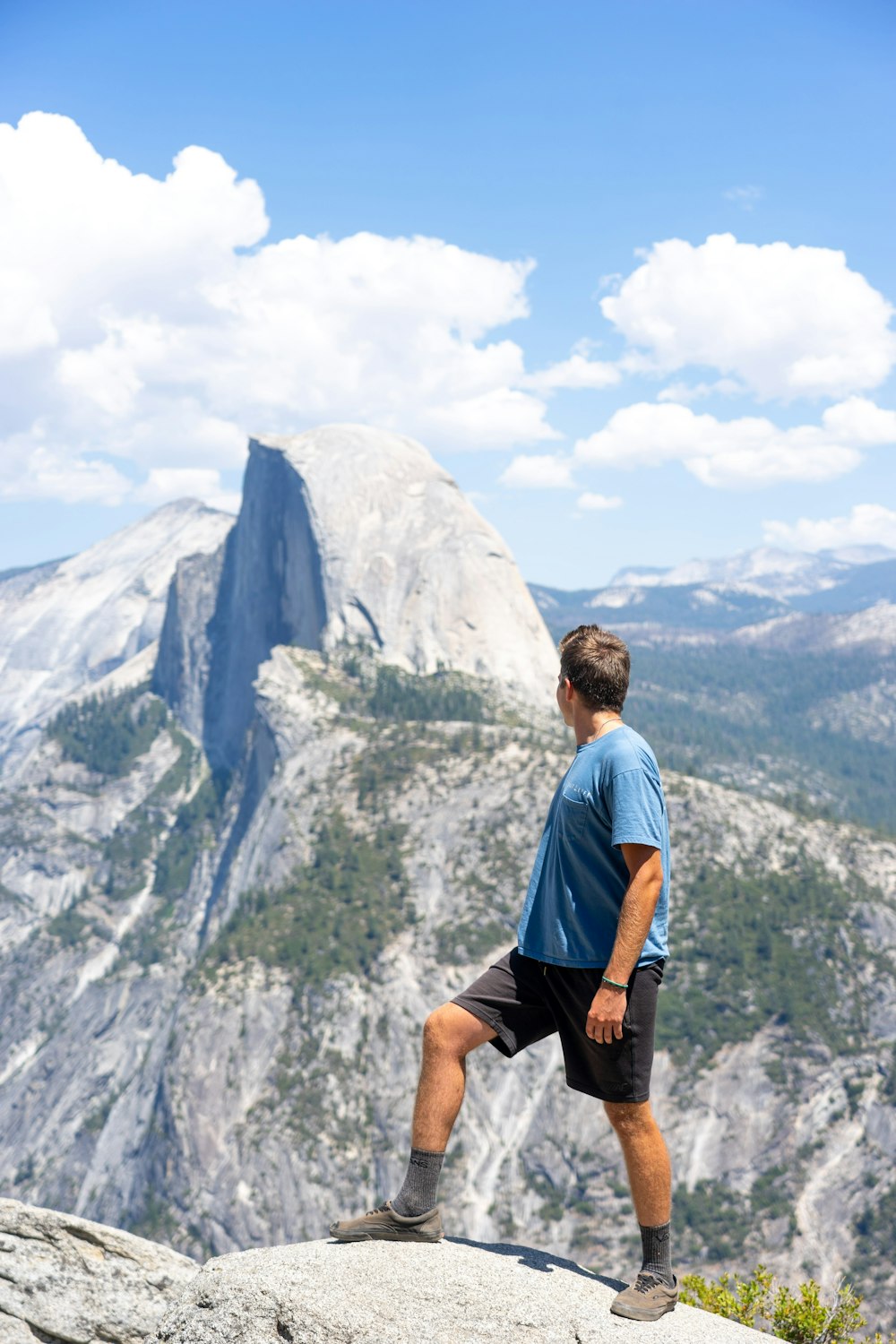 man in blue t-shirt and black shorts standing on rock formation during daytime