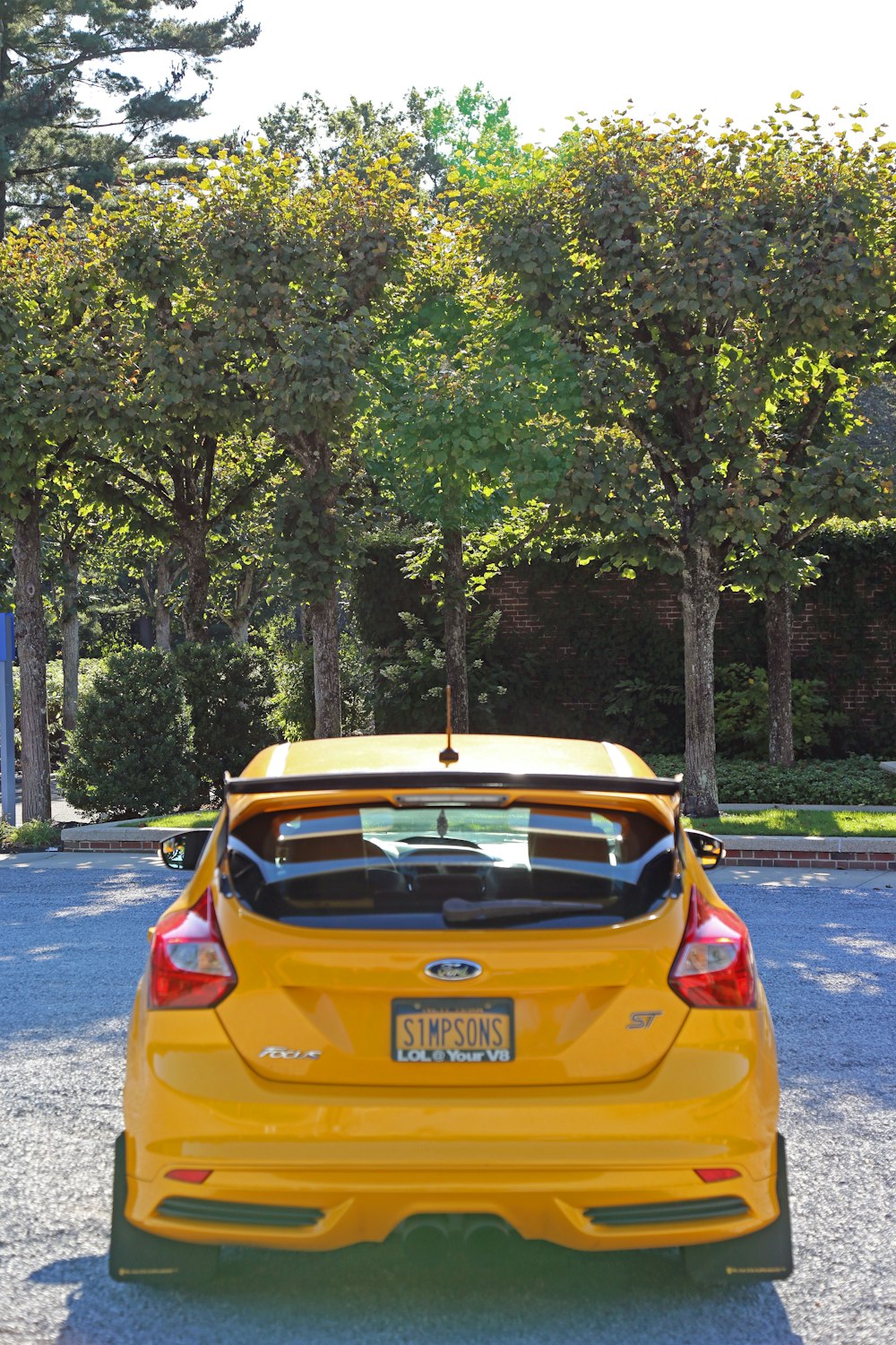 orange car parked near green trees during daytime