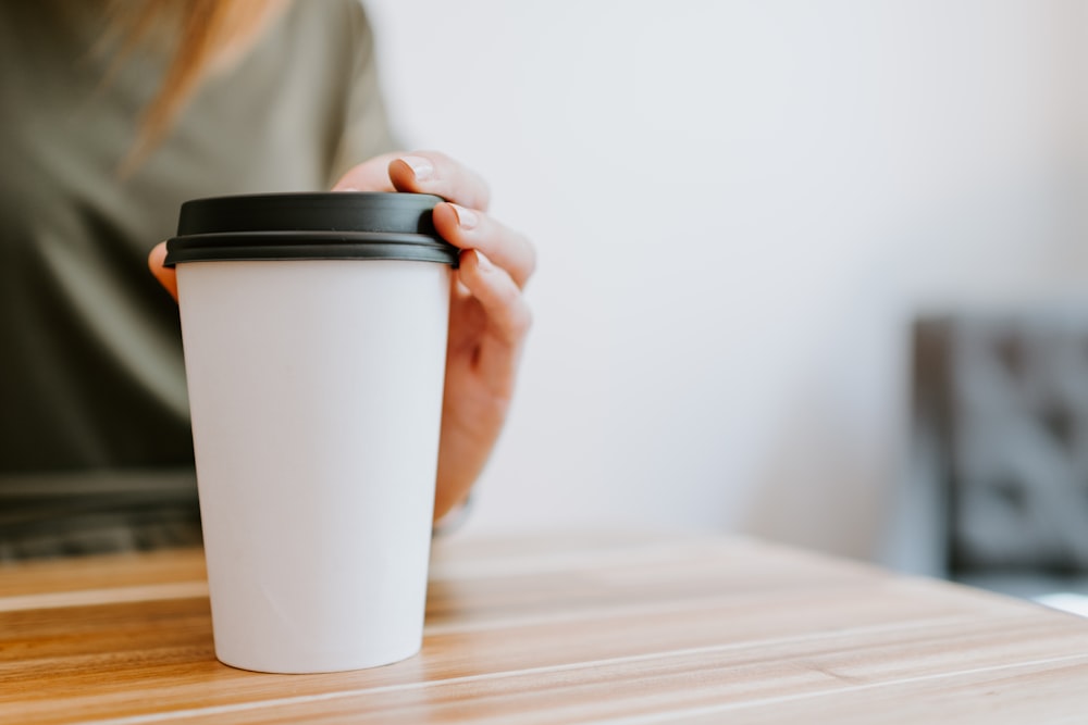 Persona sosteniendo un vaso blanco desechable