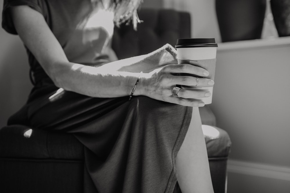 woman in white shirt holding black and white ceramic mug