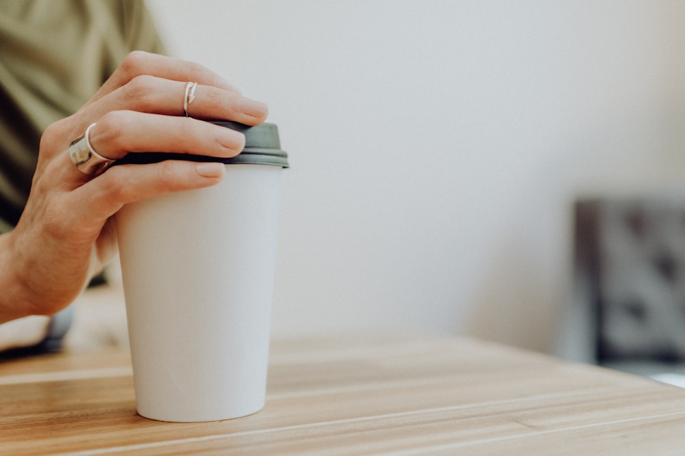 person holding white paper cup