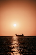 silhouette of ship on sea during sunset