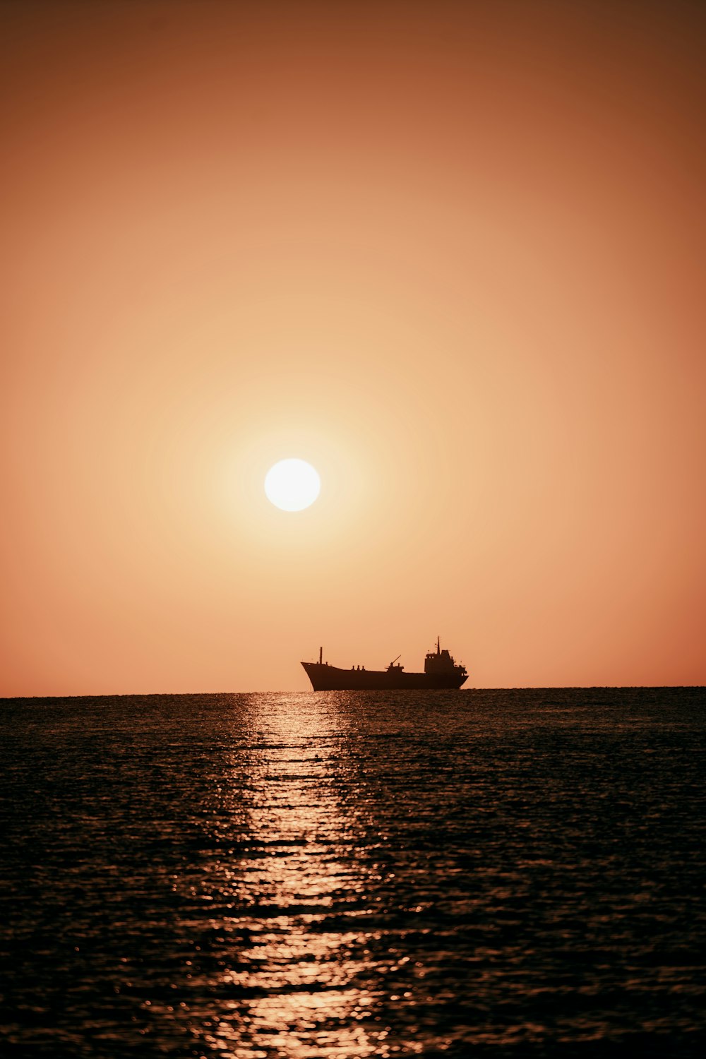 silhouette of ship on sea during sunset