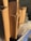 A stack of neatly arranged cardboard boxes sits in a recycling bin. The boxes are standing upright, and next to them is a clear plastic container with droplets of water on its surface. The bin is blue, and a wire fence is visible in the background.