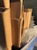 A stack of neatly arranged cardboard boxes sits in a recycling bin. The boxes are standing upright, and next to them is a clear plastic container with droplets of water on its surface. The bin is blue, and a wire fence is visible in the background.