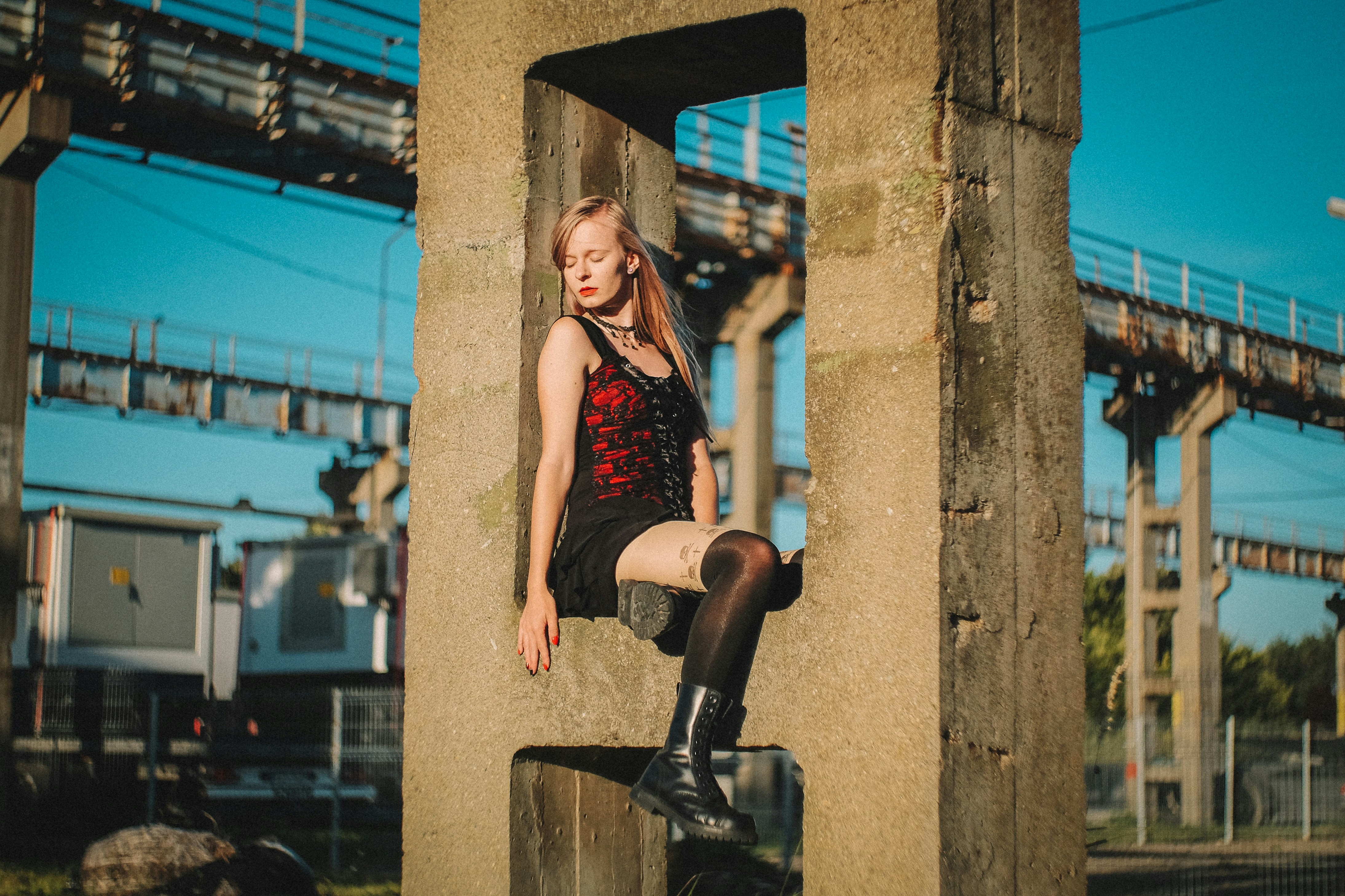 昼間、黒い金属製の支柱に座っている赤いタンクトップと黒いショートパンツを着た女性