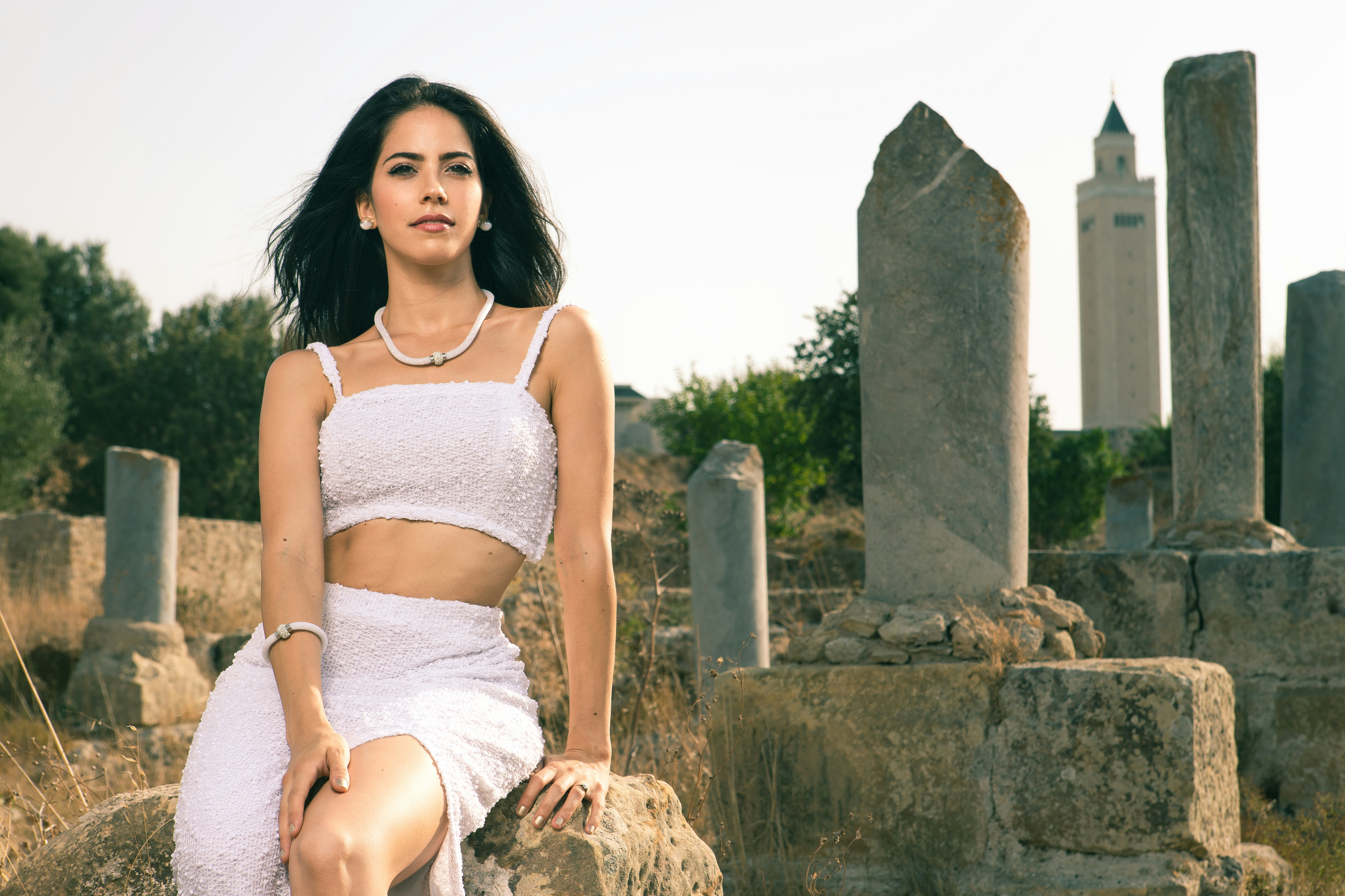 woman in white spaghetti strap top sitting on brown rock