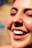 Close-up of a smiling woman with glowing skin in natural sunlight.