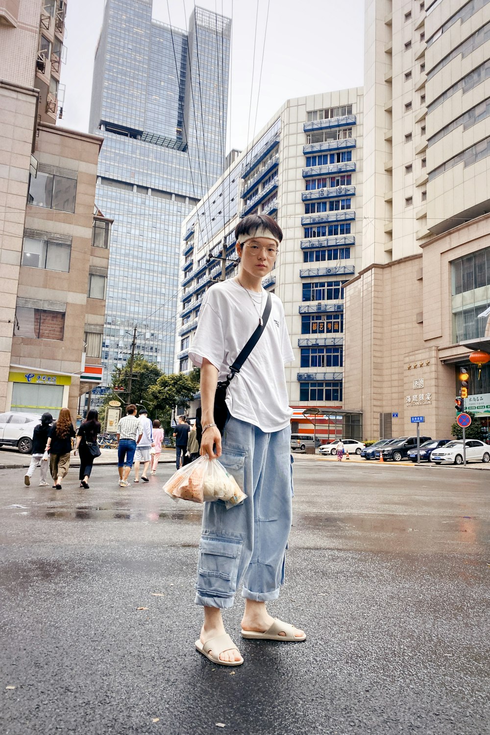 man in white crew neck t-shirt and blue denim jeans standing on gray concrete road