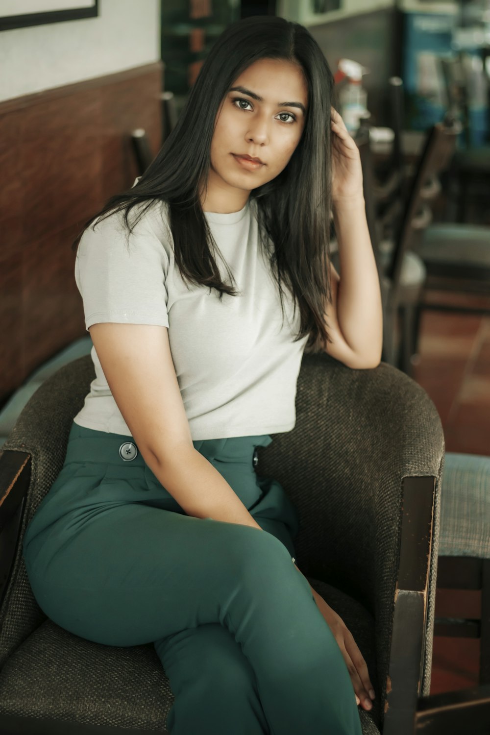 Femme en t-shirt blanc et pantalon vert assise sur un canapé marron