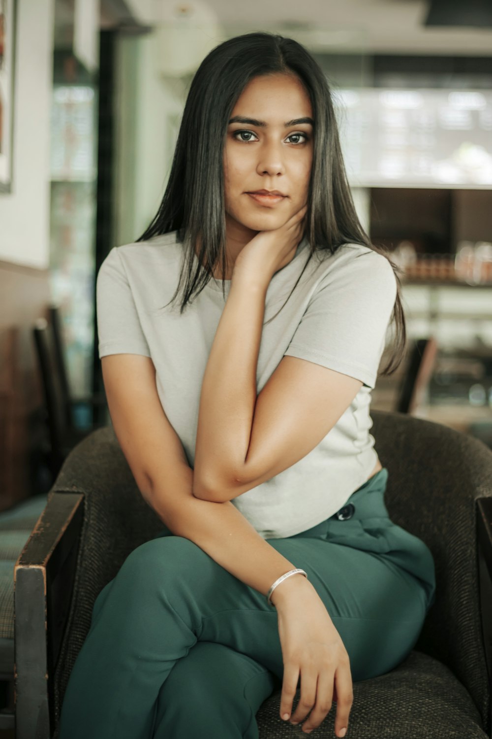 woman in white t-shirt and green pants sitting on brown sofa