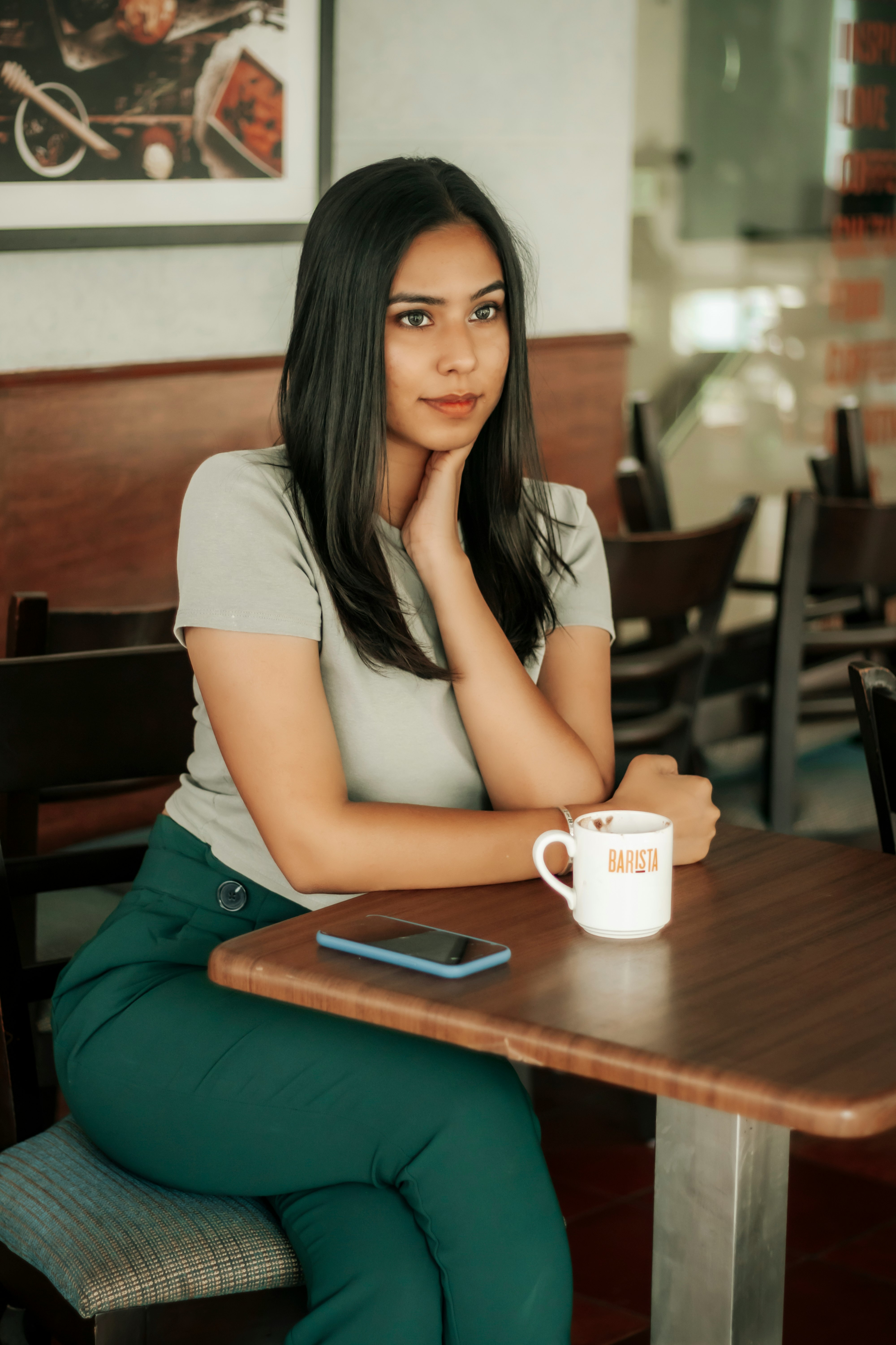 woman in white t-shirt sitting on brown wooden bench holding white ceramic mug